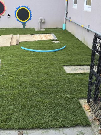 Play area with flowers, grass, and sensory path. Toys will be installed here